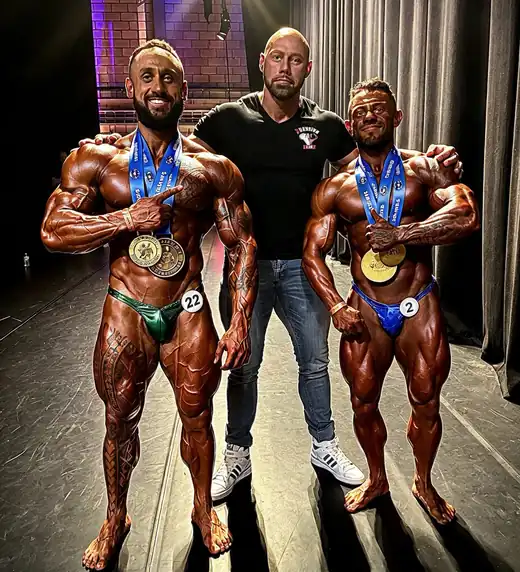 Koen met twee atleten en hun medailles bij een bodybuildingwedstrijd